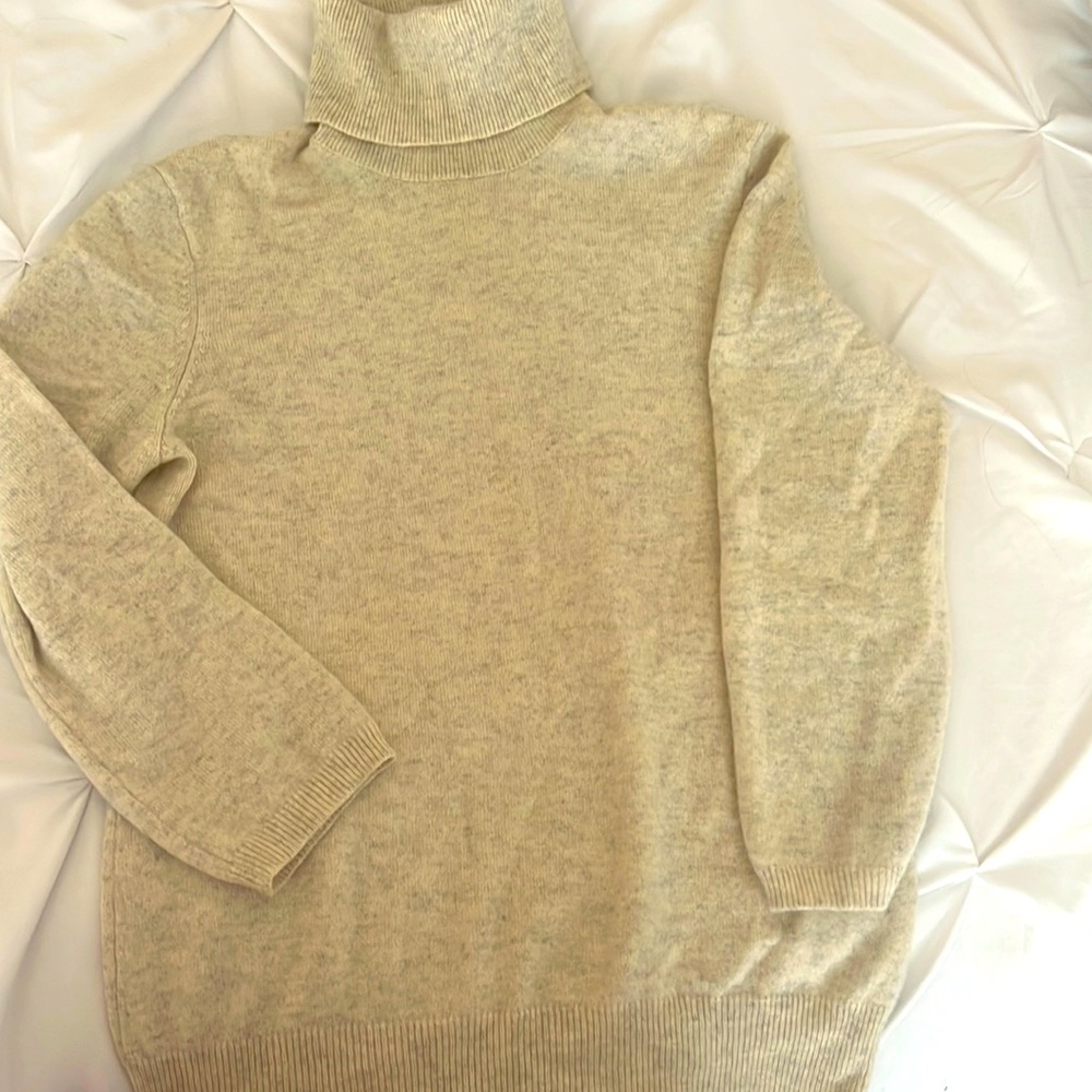 beige cashmere sweater features a cozy turtleneck